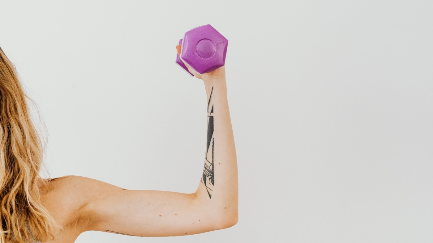 Arm curling a dumbbell representing the strength comparison of peptides vs HRT